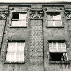 fragment ceglanej elewacji z dwiema kondygnacjami i dekoracją rzeźbiarską i pilastrami