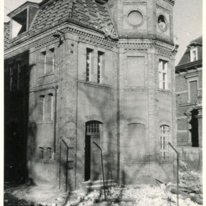 dwukondygnacyjny budynek z mansardowym dachem i wieloboczną wieżą w początkowej fazie rozbiórki