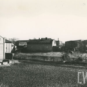 na pierwszym planie pole, w głębi niskie budynki mieszkalne i gospodarcze, z lewej fragment stodoły