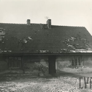 fotografia parterowego, otynkowanego domu mieszkalnego ze spadzistym dachem pokrytym dachówką, przed domem bruk