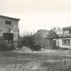 podwórze gospodarstwa, w głębi murowane zabudowania gospodarcze, dalej spadzisty dach domu mieszkalnego