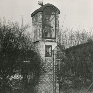 murowana, piętrowa kapliczka z figurą św. Rocha u góry i madonny na dole obrośnięta krzewami i ogrodzona drucianym płotem