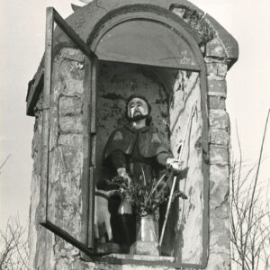 górna część murowanej, piętrowej kapliczki z figurą św. Rocha z psem we wnęce zamykanej małym okienkiem