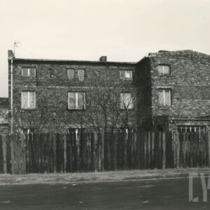 ceglany, piętrowy dom za drewnianym płotem ustawionym wzdłuż ulicy