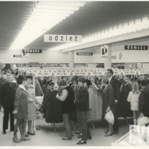 wnętrze dużego sklepu, półki z towarami, między nimi klienci