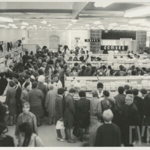 wnętrze dużego sklepu, półki z towarami, między nimi klienci