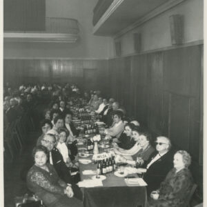 ludzie siedzą przy długich stołach, ustawionych równolegle do siebie