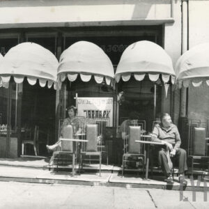 krzesła i stoliki wystawione przed lokalem gastronomicznym, przy stolikach siedzą ludzie