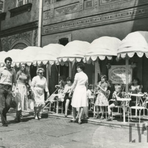 krzesła i stoliki przed lokalami, przy nich siedzą ludzie, lub spacerują