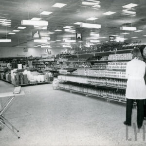 półki z artykułami w dużym sklepie, z prawej  stoją dwie kobiety