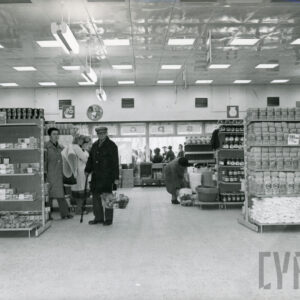 półki z artykułami w dużym sklepie, między półkami klienci