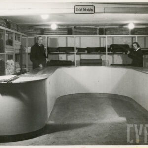 lada w kształcie litery „u”, przy niej stoi mężczyzna (z lewej) i kobieta, za nimi półki z belami materiałów