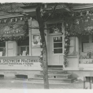 parter kamienicy, wejście do sklepu w kamienicy, po obu stronach wejścia przystrojone okna