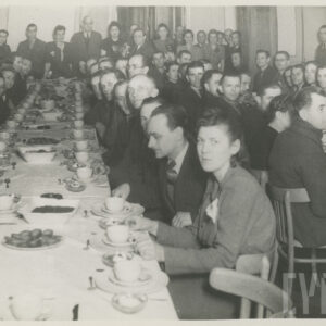 grupa kobiet i mężczyzn siedzi przy zastawionym, długim stole