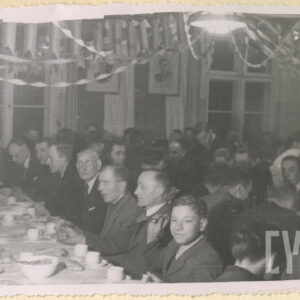 sala z długimi stołami, przy nich siedzą ludzie