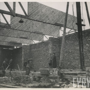 wnętrze budowanego pawilonu, ceglane ściany, drewniana konstrukcja dachu, pracujący robotnicy