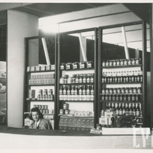 stoisko z produktami w słoikach, z przodu za ladą siedzi kobieta