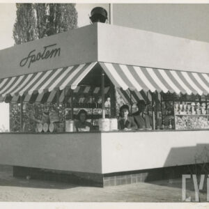 stoisko w kształcie sześcianu, z markizami nad otworami okiennymi, na ścianie napis „Społem”, za ladą stoją dwie kobiety i mężczyzna w kapeluszu