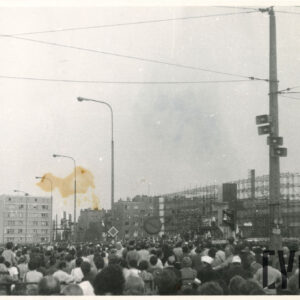 tłum ludzi zgromadzony na ulicy pomiędzy budynkami mieszkalnymi przy tymczasowym ołtarzu polowym zbudowanym na rusztowaniu; ludzie uczestniczą w mszy św.