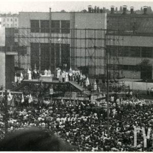 tłum ludzi zgromadzony na ulicy, pomiędzy budynkami mieszkalnymi przy tymczasowym ołtarzu polowym zbudowanym na rusztowaniu; ludzie uczestniczą w mszy świętej