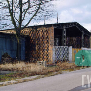 ceglana hala, przed nią metalowy, zielony kontener