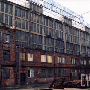 wysoka, długa przeszklona hala warsztatowa, przed nią dobudowany niższy, ceglany budynek