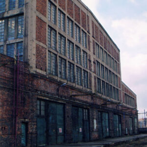 wysoki, ceglany budynek z dużą ilością przeszkleń i metalowymi dużymi bramami prowadzącymi do wnętrza hali