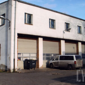 dwukondygnacyjny, otynkowany budynek, w dolnej kondygnacji trzy duże bramy wjazdowe