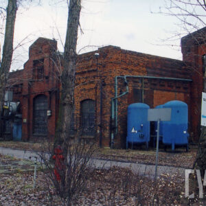 ceglana hala z ozdobnymi szczytami, przy ścianie niebieskie zbiorniki