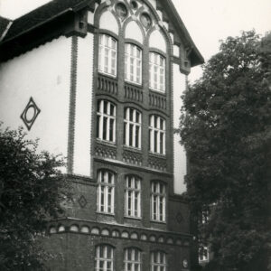 fragment elewacji trzypiętrowego budynku z bogato zdobioną elewacją i szczytem