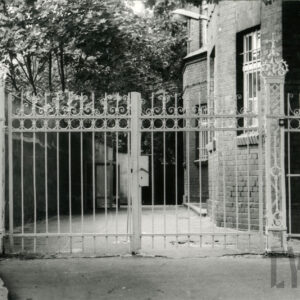 metalowa brama, bogato dekorowana, z prawej fragment ceglanej elewacji budynku