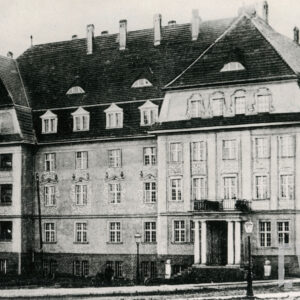 trzypiętrowy budynek z bogato zdobioną elewacją i bocznymi ryzalitami, z prawej wejście do budynku ozdobione kolumnami