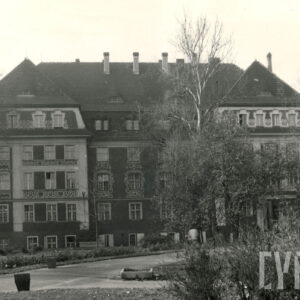 trzypiętrowy budynek z bogato zdobioną elewacją i bocznymi ryzalitami, z prawej wejście do budynku ozdobione kolumnami