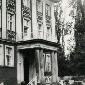 fragment elewacji z bogatą dekoracją okien, z balkonem wspartym na kolumnach, pod nim ganek z wejściem