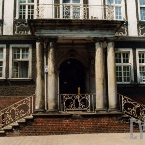 fragment elewacji z bogatą dekoracją okien, z gankiem wspartym na kolumnach, nad gankiem balkon