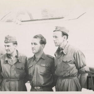 trzech mężczyzn w mundurach stoi przed samolotem
