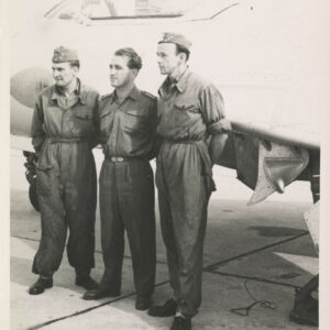 trzech mężczyzn w mundurach stoi przy samolocie myśliwskim (widoczny jego fragment)