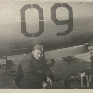 dwóch mężczyzn w mundurach kuca przy samolocie wojskowym