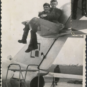 dwóch mężczyzn w mundurach siedzi na stateczniku poziomym wojskowego samolotu myśliwskiego