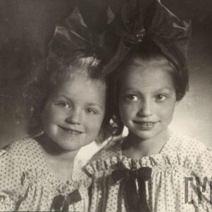 sepiowana fotografia popiersi dwóch kilkuletnich dziewczynek z ogromnymi kokardami we włosach i ubranych w sukienki w groszki