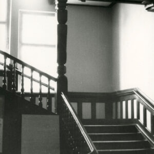 fragment drewnianych schodów z drewnianą balustradą, w głębi okna