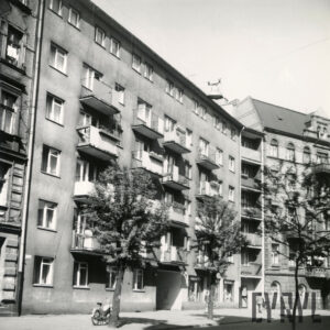 zakrzywiona ulica, przy niej kilkukondygnacyjny blok mieszkalny z balkonami