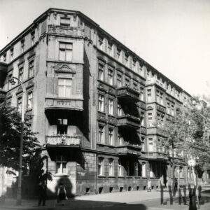 kilkukondygnacyjna kamienica narożna, przed nią drzewa