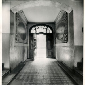 długi korytarz ze zdobioną posadzką, na ścianach malowidła, z lewej i prawej widoczne fragmenty schodów, w głębi zdobione drewniane drzwi