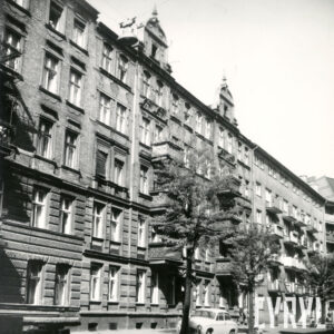 kilkukondygnacyjna kamienica i blok mieszkalny z balkonami, przed nimi drzewa