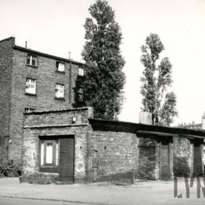 na pierwszym planie parterowy budynek ceglany, za nim kilkukondygnacyjna kamienica ceglana