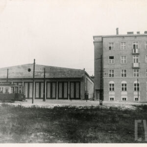 z lewej hala, przed nią stoi tramwaj, z prawej strony trzypiętrowy budynek mieszkalny