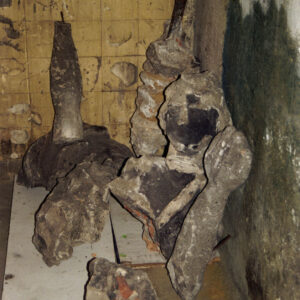fragmenty zniszczonej kamiennej rzeźby leżące na posadzce i częściowo oparte o ścianę