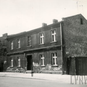 dwukondygnacyjny budynek mieszkalny, z prawej fragment drewnianego ogrodzenia