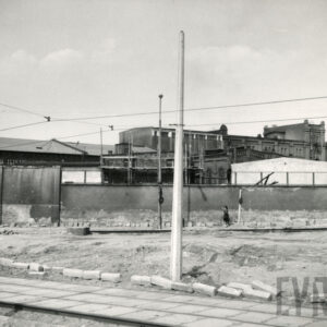 murowany płot, w głębi kilkukondygnacyjne budynki